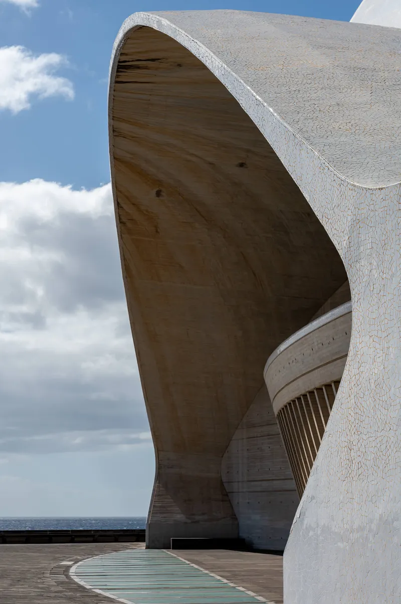 The Auditorio de Tenerife viewed from the side, its curved concrete wings framing the Atlantic Ocean