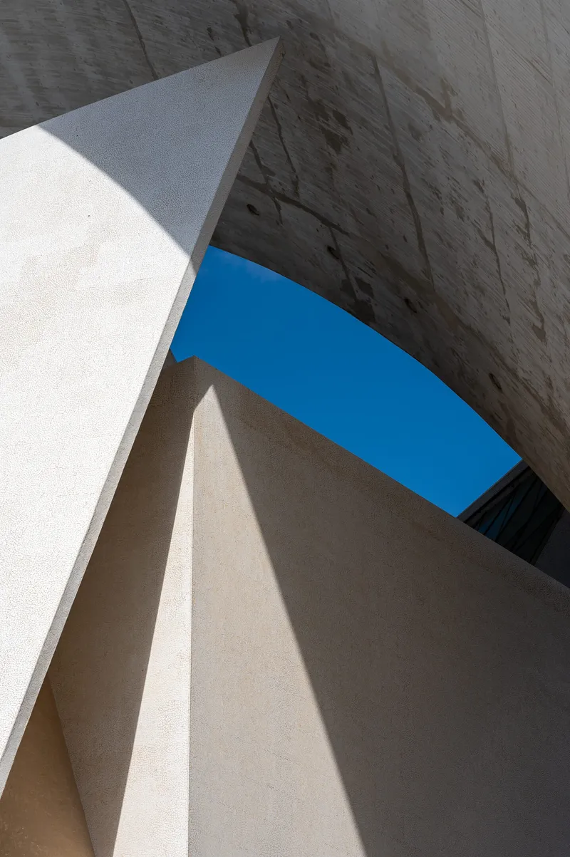 Abstract view looking up through concrete walls to a crescent of blue sky at the Auditorio de Tenerife