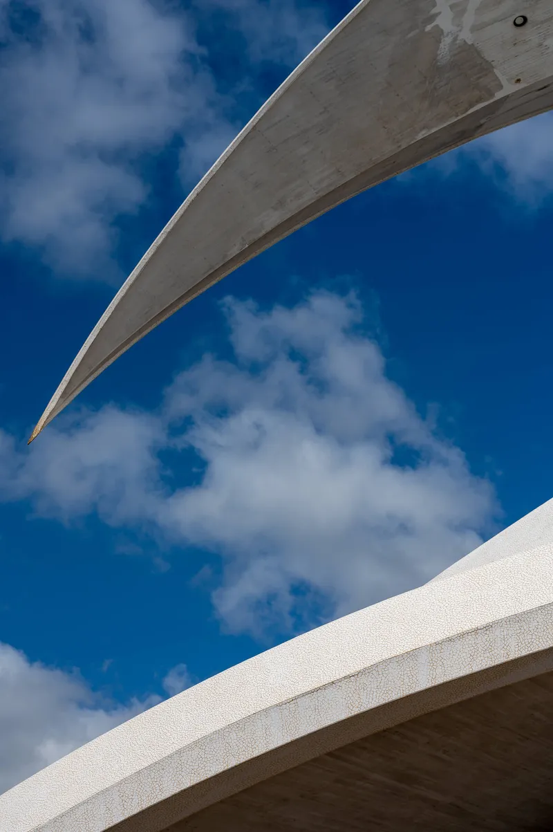 The tip of the main arch of the Auditorio de Tenerife against bright blue sky and white clouds