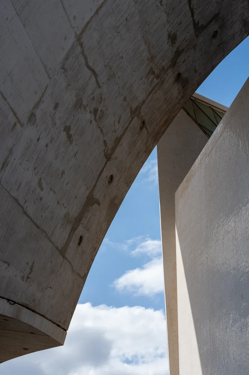 Looking up through a gap between two curved concrete surfaces of the Auditorio de Tenerife