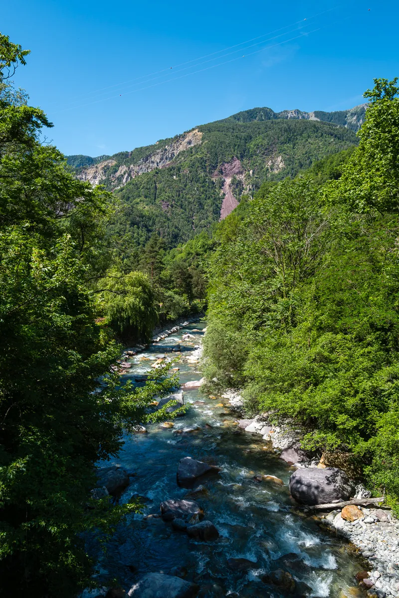 The Tinée river running clear over pale stones below Saint-Sauveur-sur-Tinée, green slopes rising behind, Alpes-Maritimes, Leica Q2