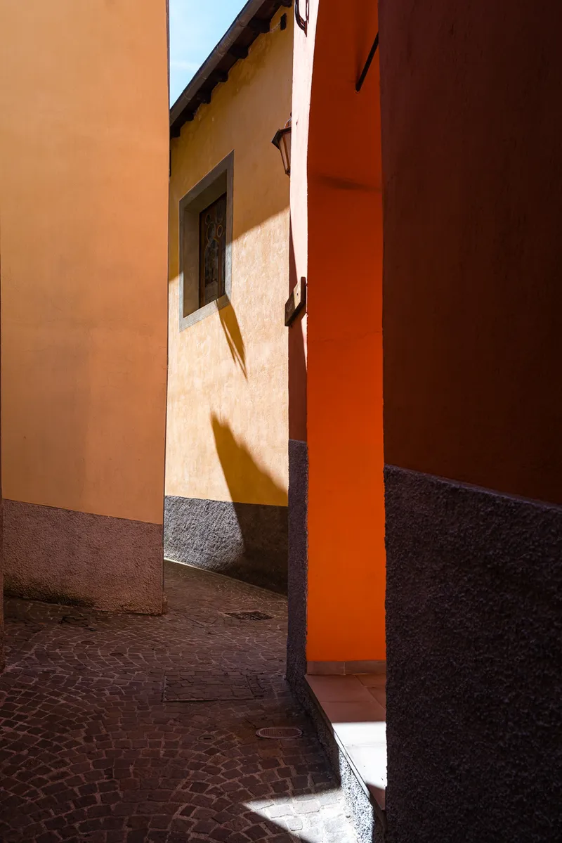 Afternoon light and shadow on ochre and orange painted walls in a narrow lane of Saint-Sauveur-sur-Tinée, Alpes-Maritimes, Leica Q2