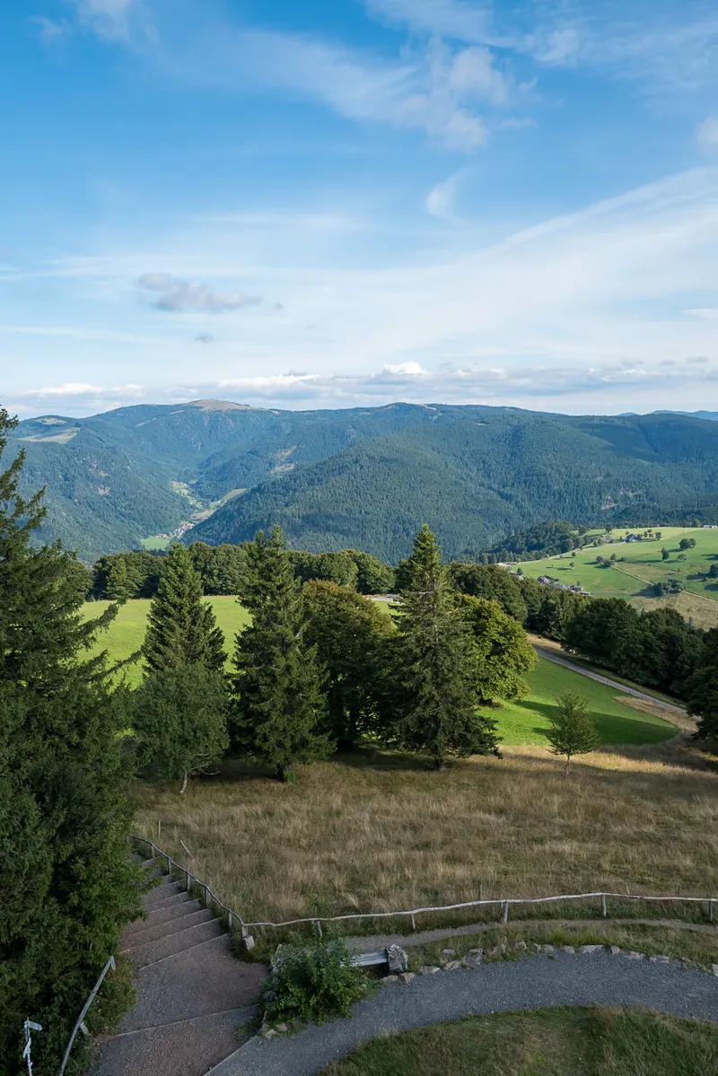 Steps and viewing area below the Schauinsland observation tower looking toward Black Forest peaks and green valleys, Leica Q2