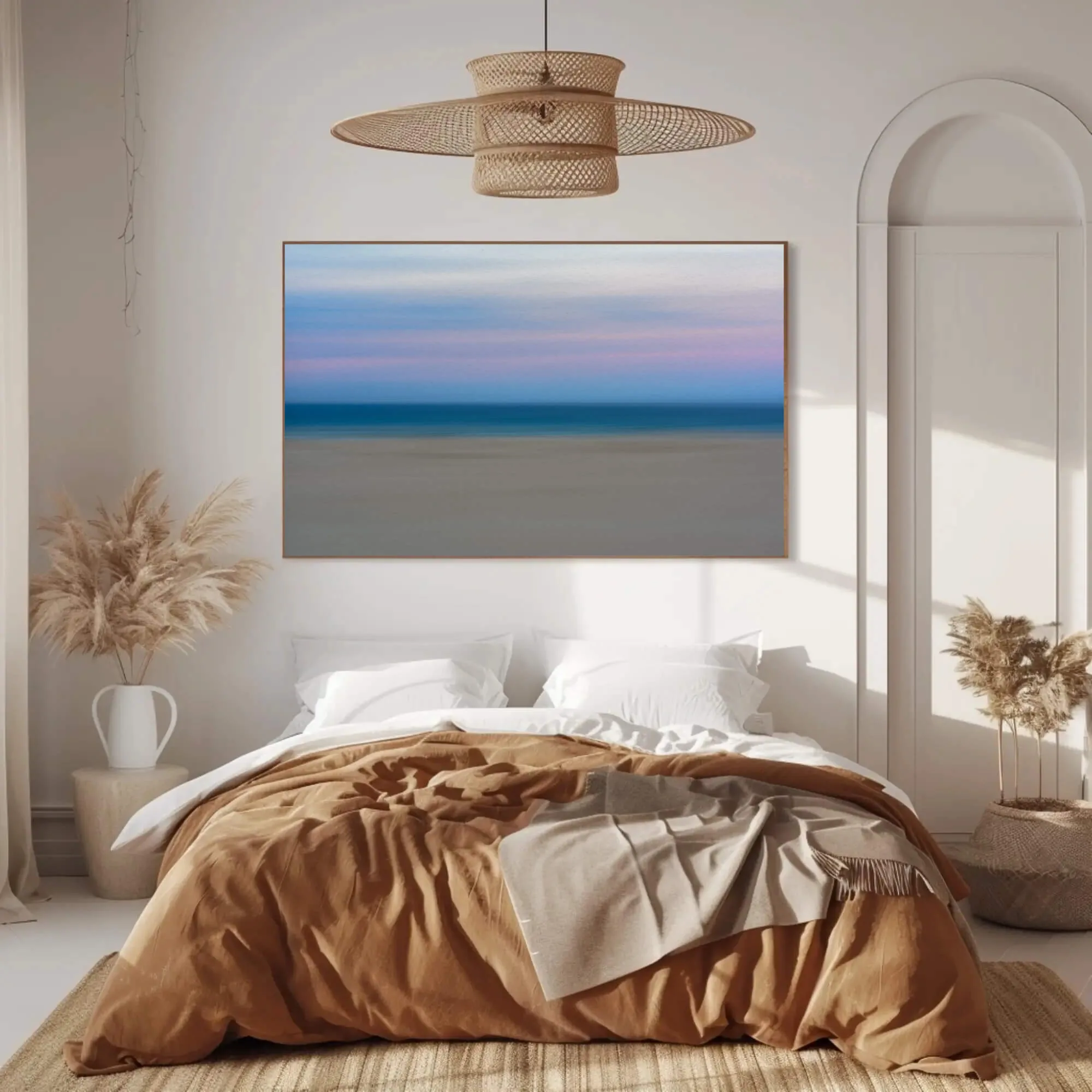 Raya hung above a double bed, a horizontal photography print of sand, sea and sky by Markus H. Green